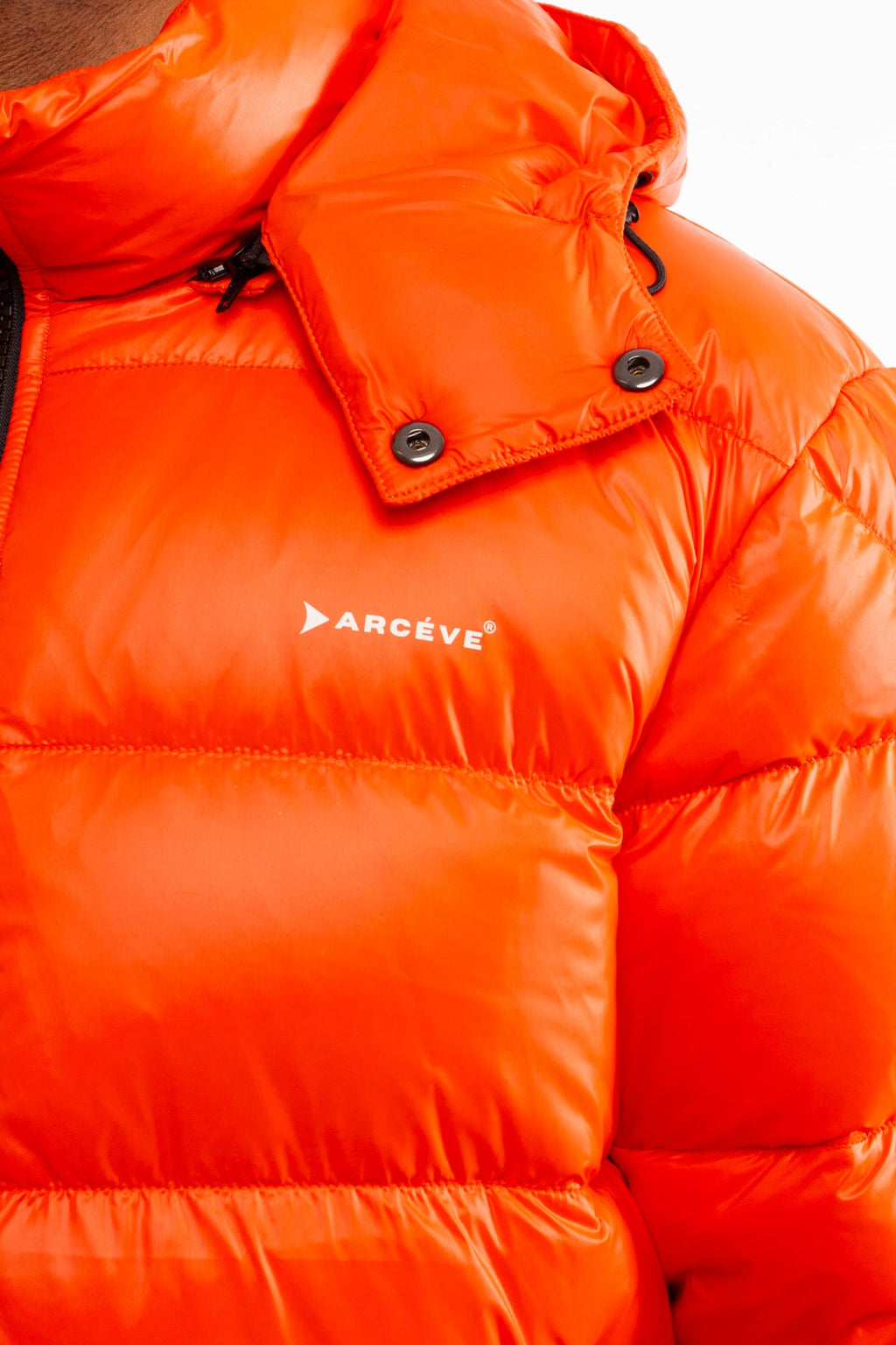 ARCÉVE The Mont Jacket - Close-up of the signature ARCÉVE logo on the chest - Orange