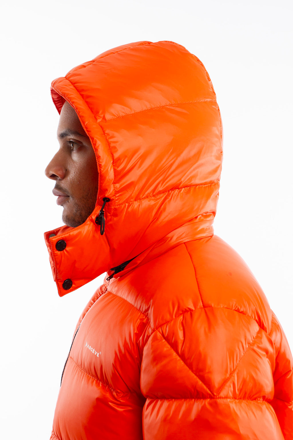 ARCÉVE The Mont Jacket - Close-up of the signature ARCÉVE logo on the chest - Orange